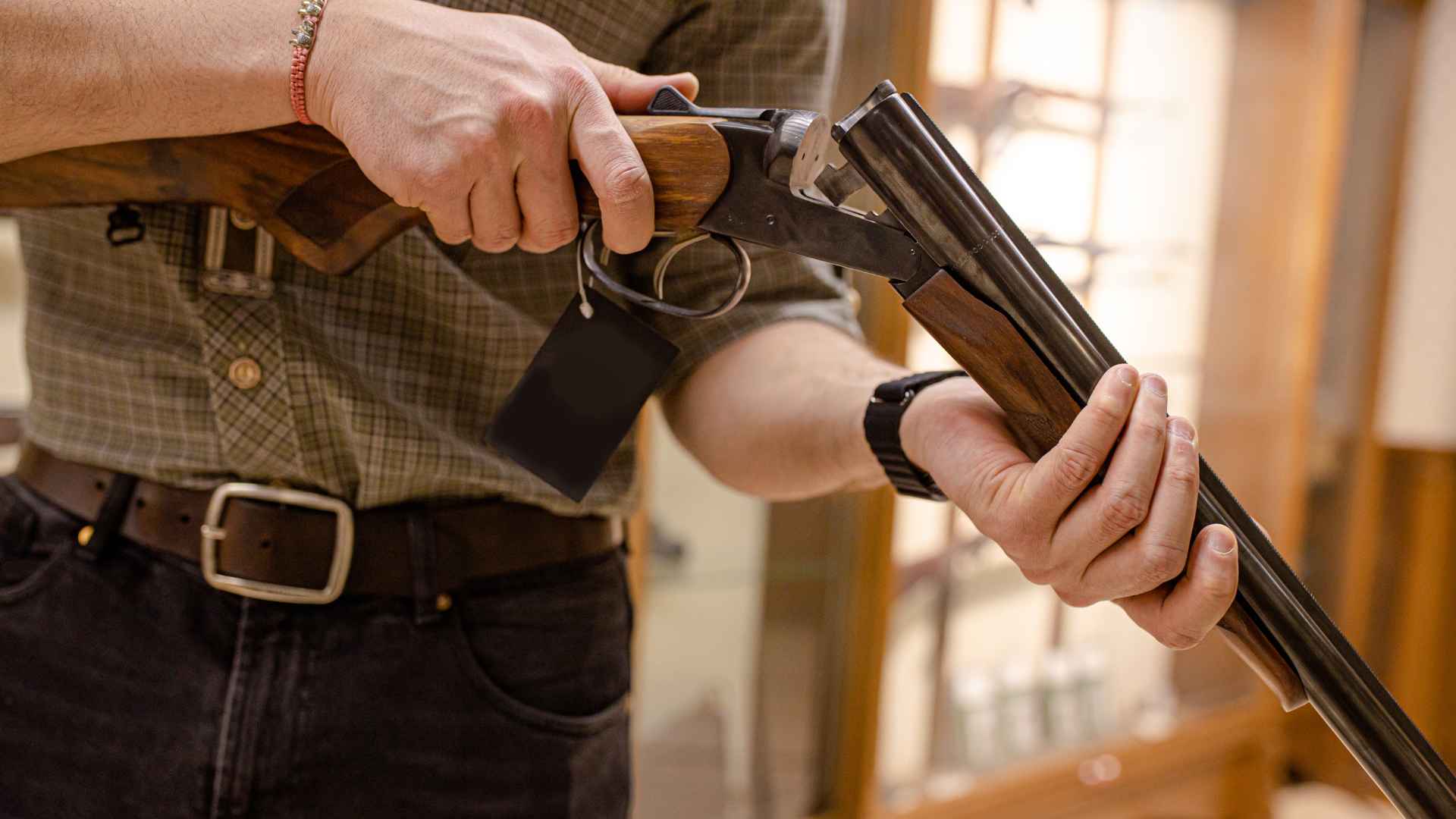 Gun store employee handling a shotgun with a price tag in a firearms retail store